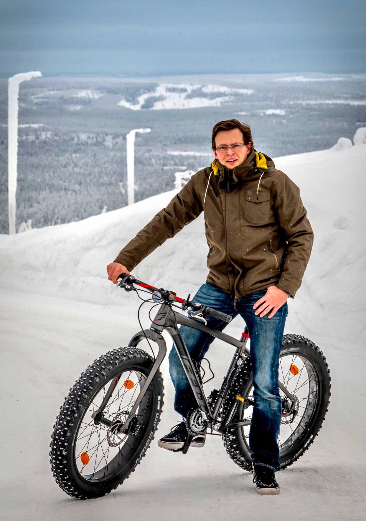 A founding member of Digitarvike, Janne Rajala, photographed on top of fatbike at the top of a snowy mountain in a ski resort in Lapland.